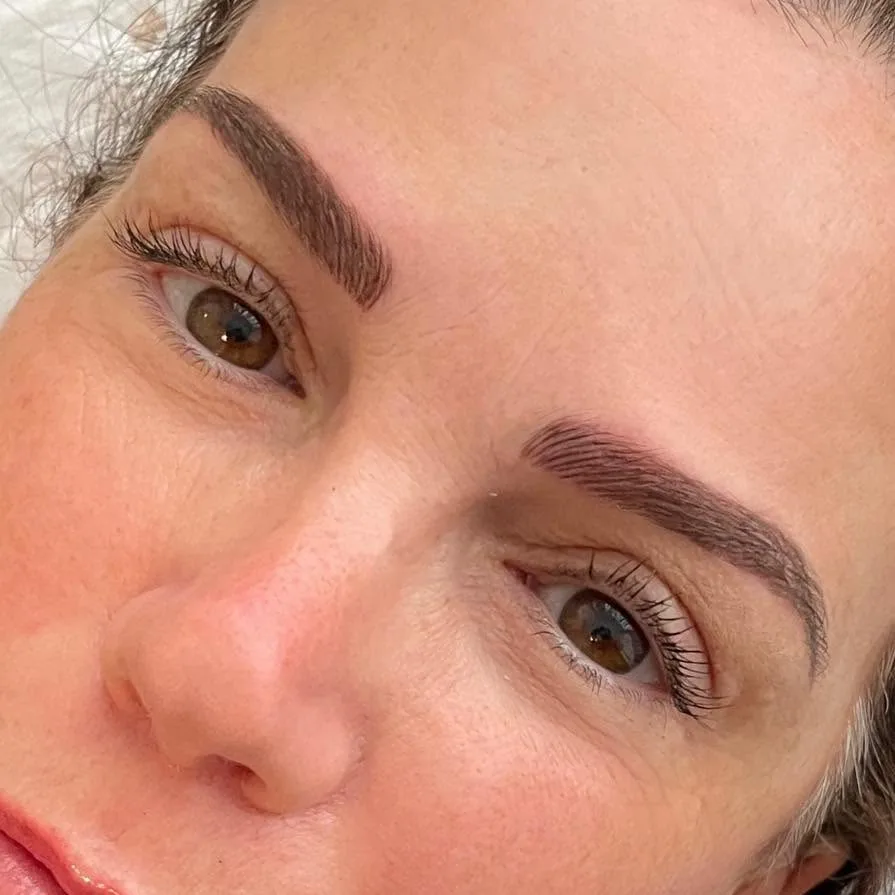 Natural hair-stroke brow tattooing result — both brows, close macro